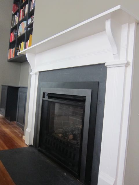 A reclaimed mantel was installed in a new living room renovation to make it look like it came with the old house