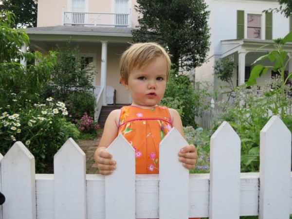 Diana in front of our house with Shasta daisies and the peach tree in the background.